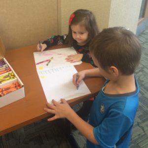 Two children are sitting at a table and drawing.