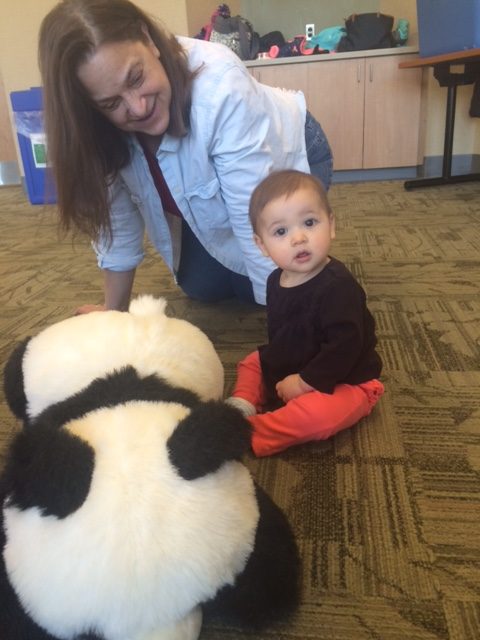 A woman and baby playing with a panda bear.