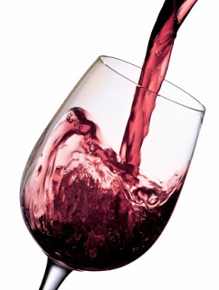 A glass of red wine is being poured into it.