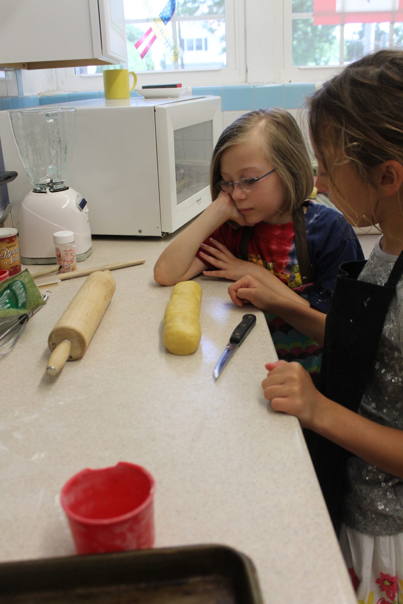 Two girls are making cookies on a counter.