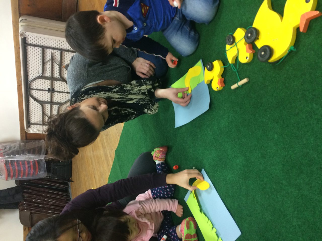 A group of people sitting on the ground with cars.