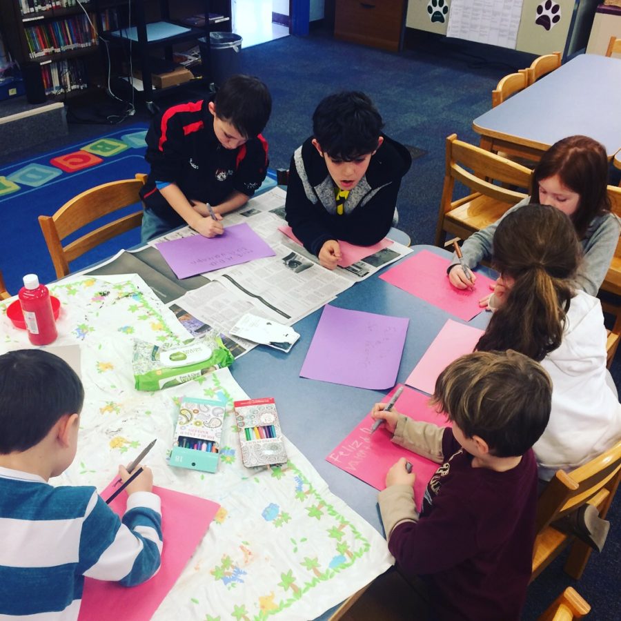 A group of children sitting at a table with papers.