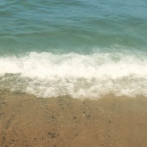 A beach with waves coming in from the ocean.