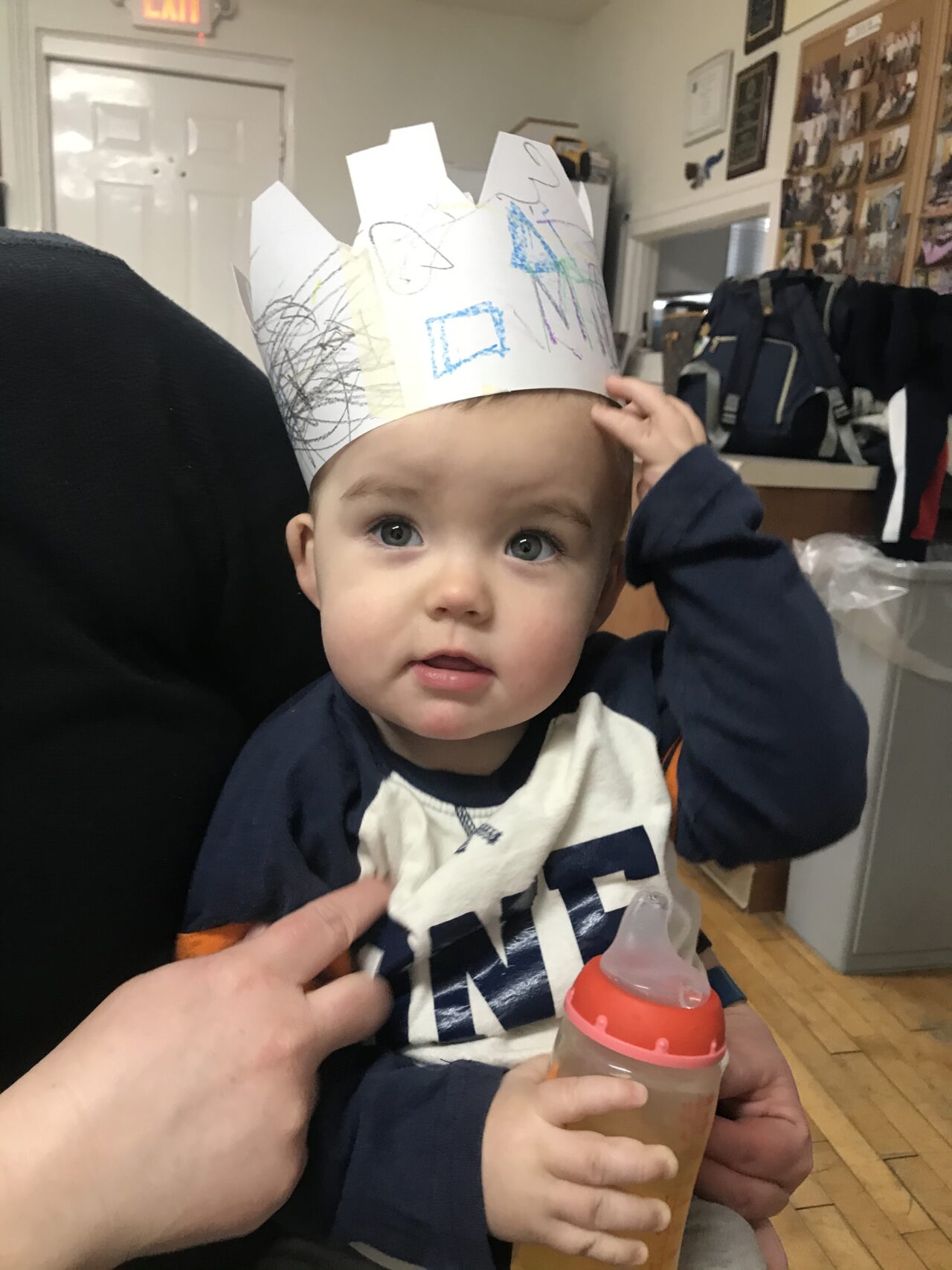 A baby wearing a paper crown on his head.