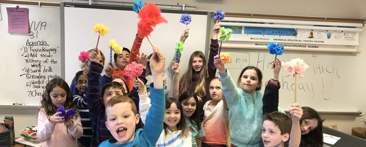 A group of children holding up their hands in the air.