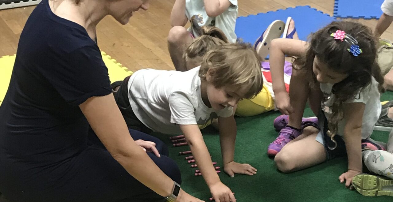 A woman sitting on the floor with children.