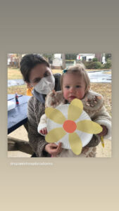 Here's a short alt tag for the image: `Woman and toddler holding flower craft`