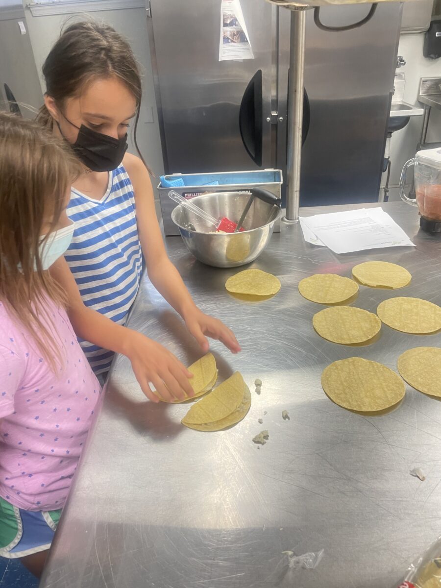 Two girls making tortillas in a kitchen.