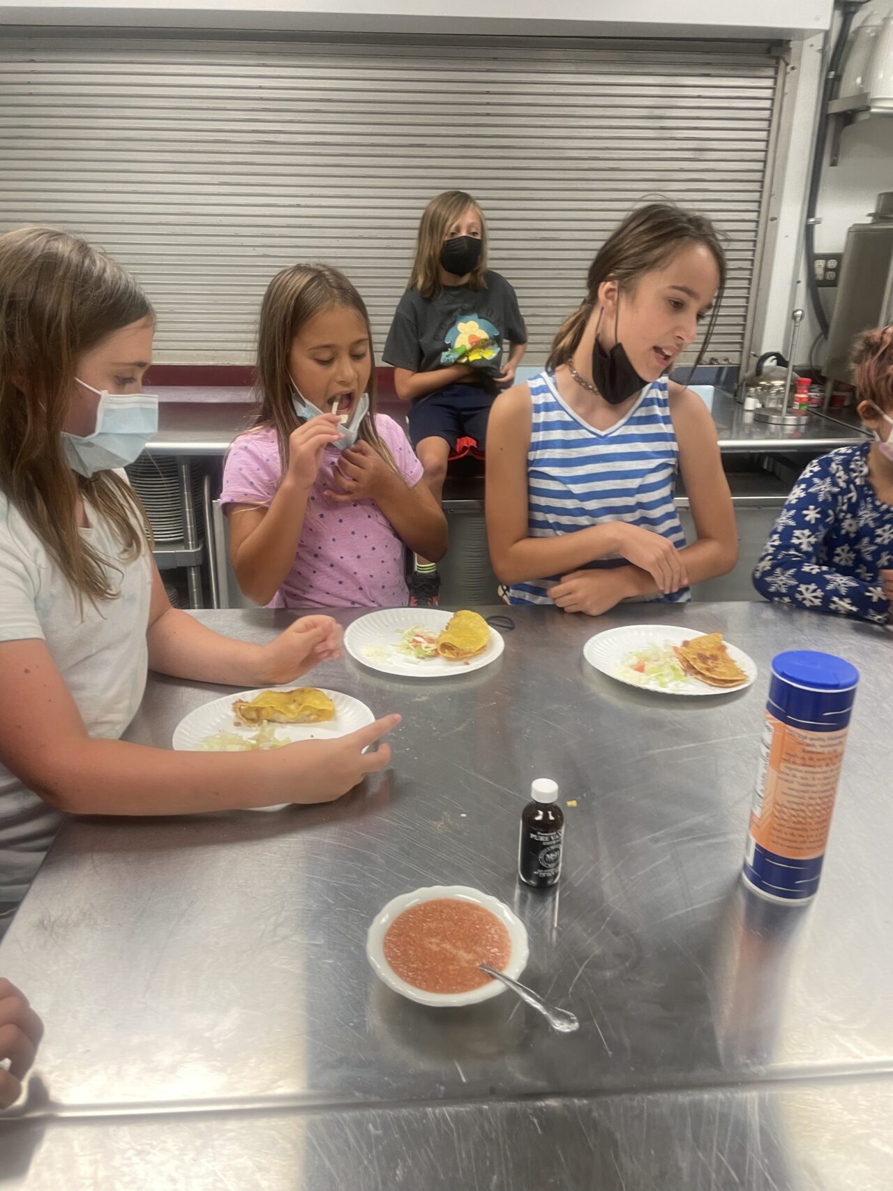 A group of children sitting at a table eating food.