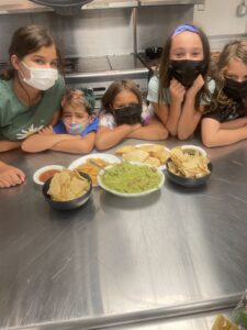 Here's a short alt tag for the image: `Kids proudly display their homemade guacamole and chips.`