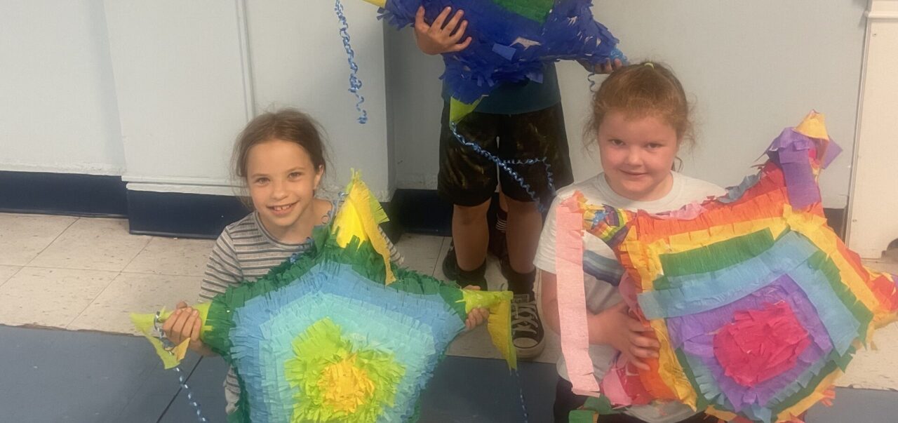 A group of children holding colorful kites in the shape of stars.