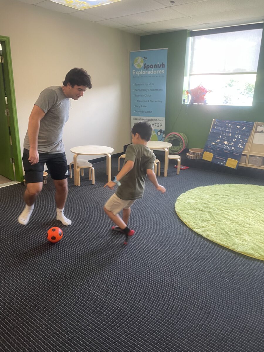 Two young men playing soccer in a room.